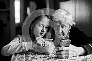 Cute little girl shows her great-grandmother a smartphone.