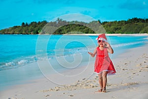 Cute little girl sing and clap hands, celebrating christmas on tropical beach