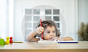 Cute little girl sit at desk at home doing homework, reading, writing and painting. Children paint. Kids draw.