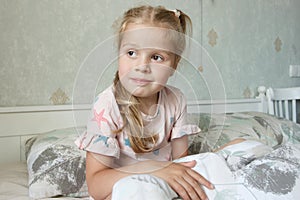 Cute little girl sitting on the bed and smiling. Concept of health care