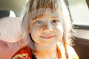 Cute little girl sitting in car seat and smiling. Travel and child transportation safety