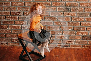 Cute little girl sitting on a chair in a new living room.