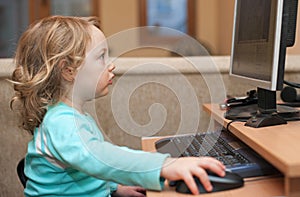 Little girl playing with computer keyboard and mouse