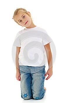 A little girl is sitting on the floor in a clean white T-shirt.