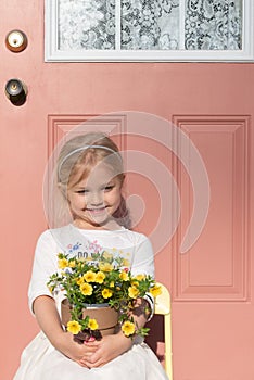 Cute little girl sitting in front of a pink door