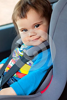 Cute little girl is sitting in her car safety seat