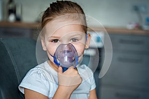 Cute little girl are sitting and holding a nebulizer mask leaning against the face, airway treatment concept