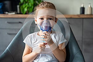 Cute little girl are sitting and holding a nebulizer mask leaning against the face, airway treatment concept