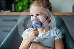 Cute little girl are sitting and holding a nebulizer mask leaning against the face, airway treatment concept