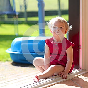 Cute little girl sitting at opened sliding door