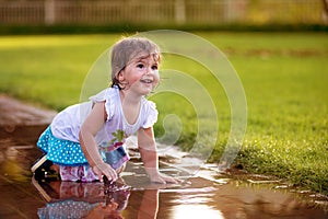 Cute little girl sitting in puddle