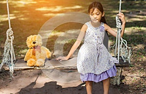 Cute little girl sitting swings , teddy bear sitting with her,little girl pointed to the tree
