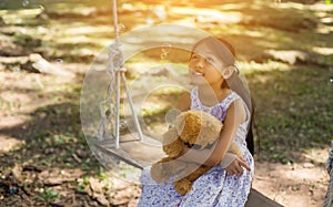 Cute little girl sitting swings , teddy bear sitting with her,little girl pointed to the tree