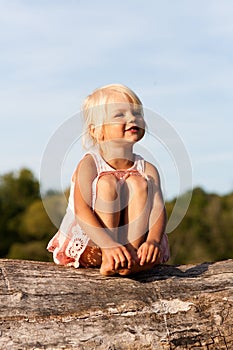 Cute little girl sitting on tree