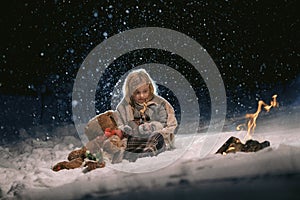 Cute little girl warming herself by the fire in the winter evening