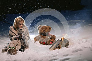 Cute little girl warming herself by the fire in the winter evening