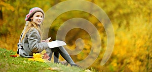 Cute little girl sketching outside on beautiful autumn day. Happy child playing in autumn park. Kid drawing with colourful pencils