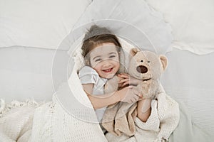 A cute little girl is sleeping in a bed with a Teddy bear toy