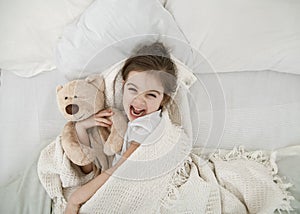 A cute little girl is sleeping in a bed with a Teddy bear toy