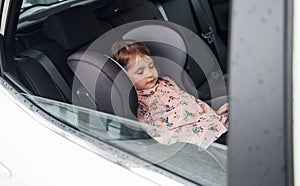 Cute little girl sleeping inside of the car. Conception of traveling and vaccation photo