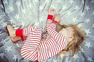 Cute little girl sleeps in pajames on bed