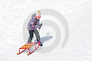 Cute little girl sliding on a sled on snow