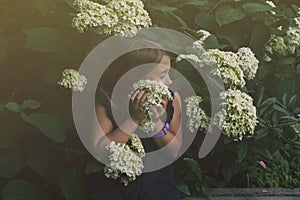 Cute little girl smelling lilac