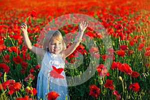 Cute little girl smiles and raises her arms upwards for joy. poppy fields in Italy