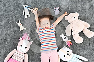 Cute little girl and soft toys on floor