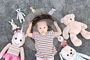 Cute little girl and soft toys on floor, top view