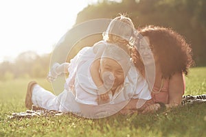 A cute little girl is spending time with her beloved grandfather and grandmather in the park. They had a picnic on the