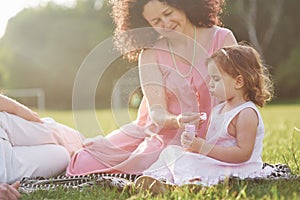 A cute little girl is spending time with her beloved grandfather and grandmather in the park. They had a picnic on the