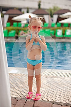 Cute little girl standing alone near swimming pool