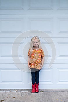 Cute little girl standing in the driveway in red cowboy boots