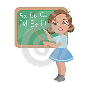 Cute little girl standing near the blackboard and writing letters of the English alphabet, a colorful character isolated