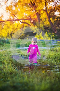 Cute little girl standing near a puddle