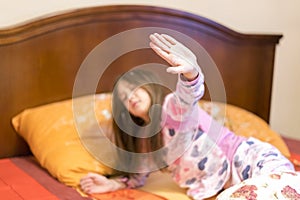 Cute little girl stretching her arms happily with a smile from waking up in her bed. child sleepy yawning in bed. Sleepy little