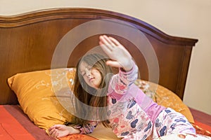 Cute little girl stretching her arms happily with a smile from waking up in her bed. child sleepy yawning in bed. Sleepy little