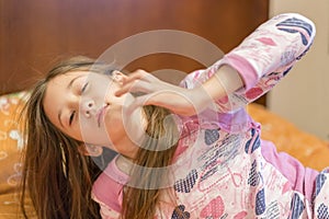 Cute little girl stretching her arms happily with a smile from waking up in her bed. child sleepy yawning in bed. Sleepy little