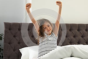 Cute little girl stretching after sleep