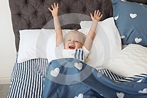 Cute little girl stretching after sleeping in bed