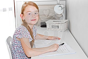 Cute little girl studying at home and smiling