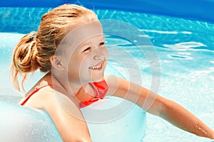 Cute little girl swims in the pool on a rubber ring on a sunny day. Child on summer vacation