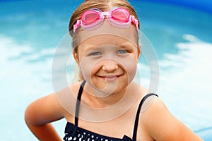 Cute little girl swims in the sea. A child with glasses smiles and looks into the camera