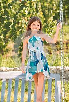 Cute little girl on a swing. Smiling child playing outdoors in summer. Happy kids swinging at the park. Happy kid having