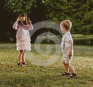 Cute little girl taking a phto of her younger brother