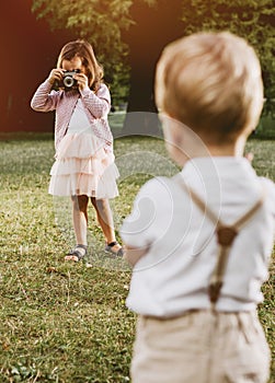 Cute little girl taking a phto of her younger brother