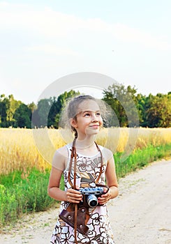 Cute little girl taking pictures with old film camera. Pretty c