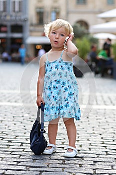 Cute little girl talking on mobile phone in the city