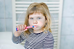 Cute little girl with a toothbrush in her hand cleans her teeth and smiles. Funny happy healthy child learning morning